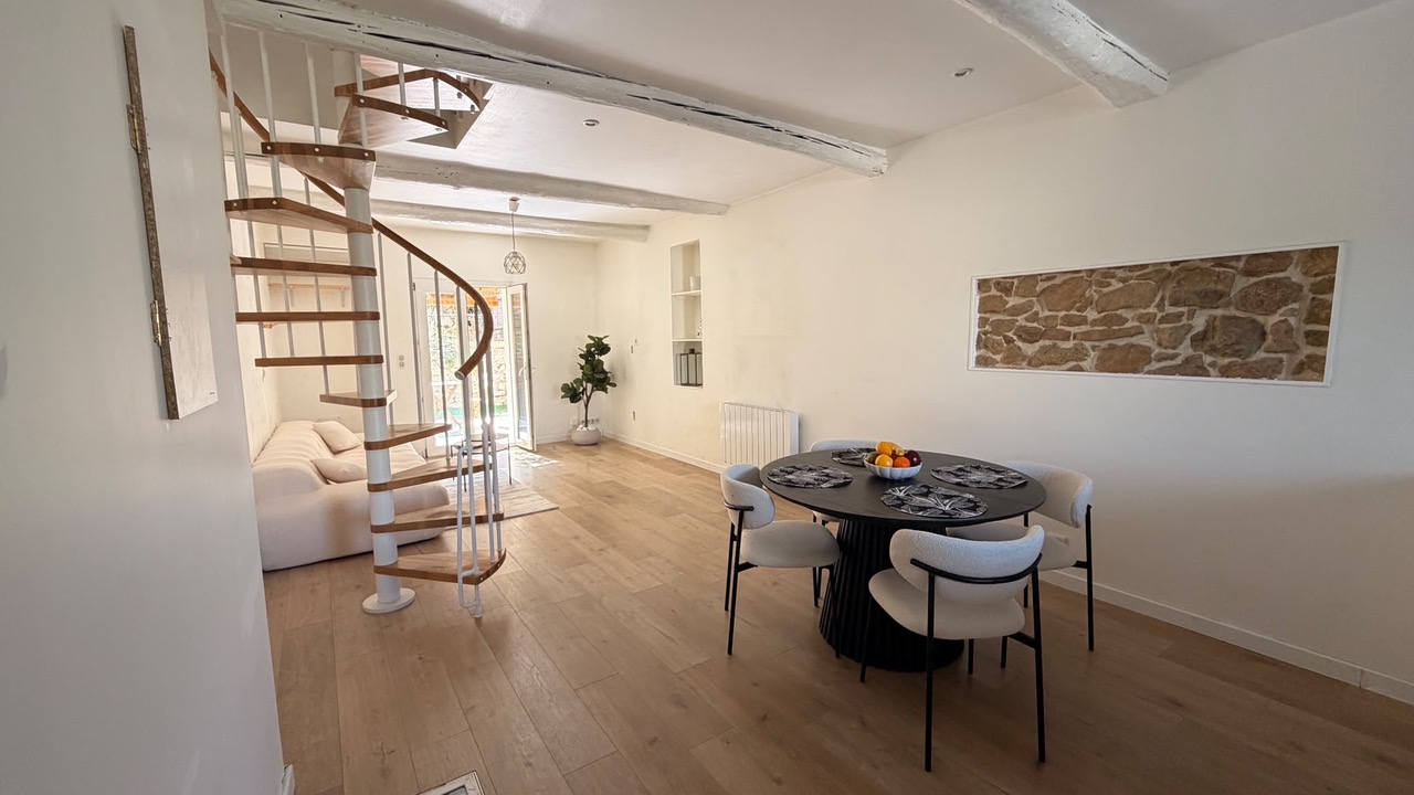 Pièce de vie meublée Fuveau avec table ronde et canapé sous escalier